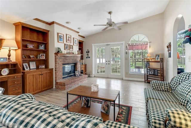 living room featuring a ceiling fan, vaulted ceiling, french doors, a fireplace, and wood finish floors