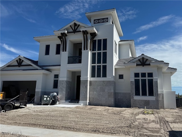 view of front of property featuring a garage, a balcony, and stucco siding