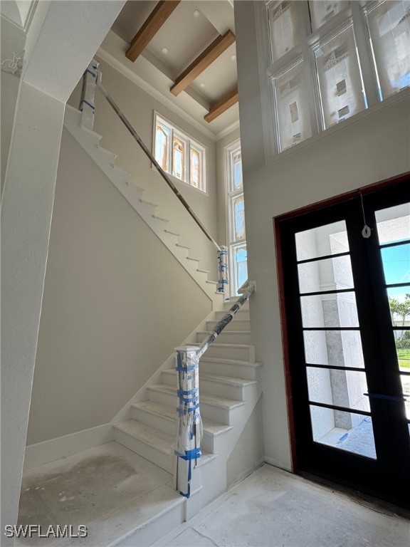 foyer entrance featuring a towering ceiling, stairs, and french doors