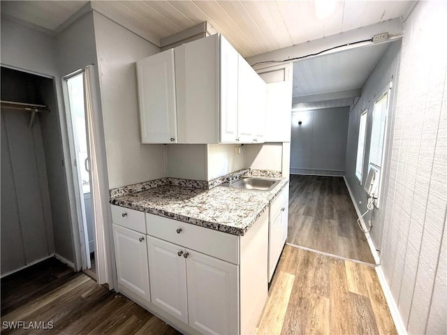 kitchen featuring light wood finished floors, beam ceiling, white cabinetry, a sink, and wood ceiling