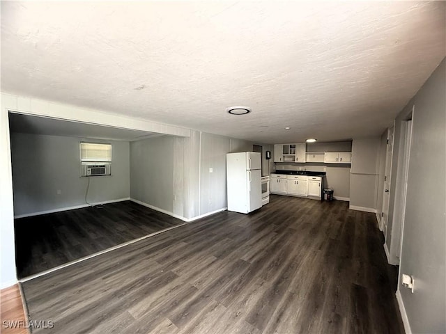 unfurnished living room with cooling unit, dark wood-style flooring, baseboards, and a textured ceiling