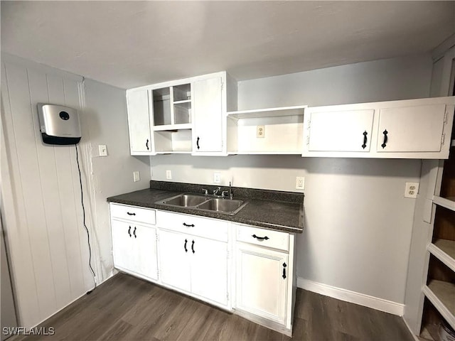 kitchen with a sink, dark countertops, dark wood-style floors, and open shelves
