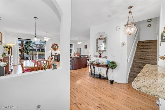 interior space featuring a ceiling fan, arched walkways, stairway, and light wood finished floors