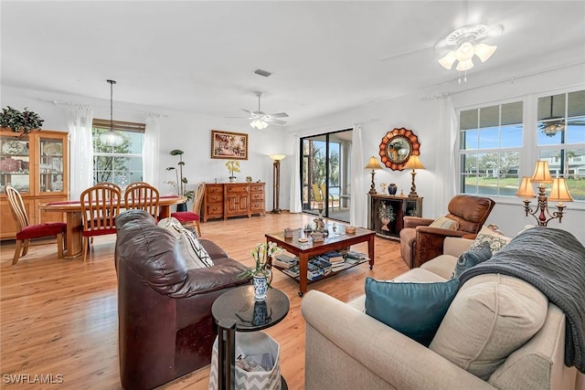 living room featuring light wood finished floors, plenty of natural light, and a ceiling fan