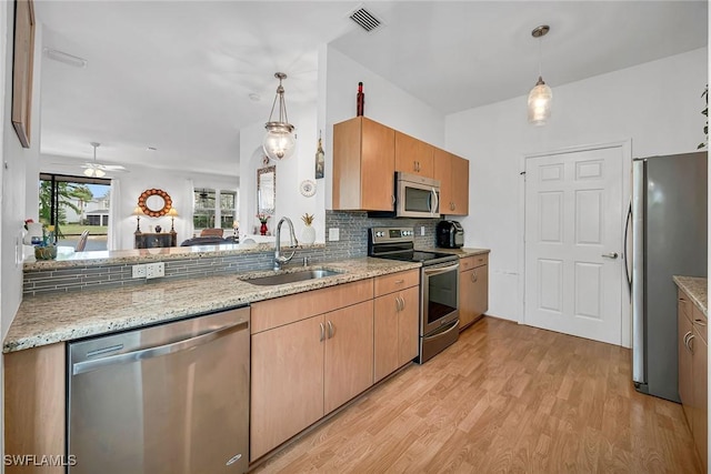 kitchen featuring a sink, visible vents, light wood-style floors, appliances with stainless steel finishes, and backsplash