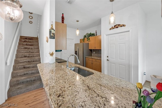 kitchen featuring visible vents, light wood-style flooring, backsplash, a sink, and stainless steel fridge with ice dispenser