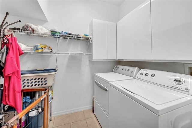 laundry area featuring light tile patterned floors, washer and clothes dryer, cabinet space, and baseboards