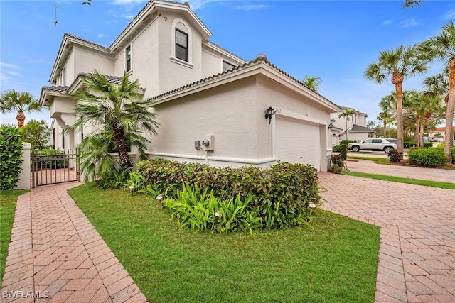 view of property exterior with a garage, a gate, decorative driveway, and stucco siding