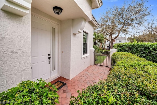 property entrance with a gate and stucco siding