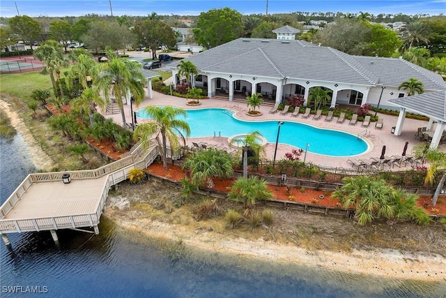 community pool with a gazebo, a patio area, fence, and a water view