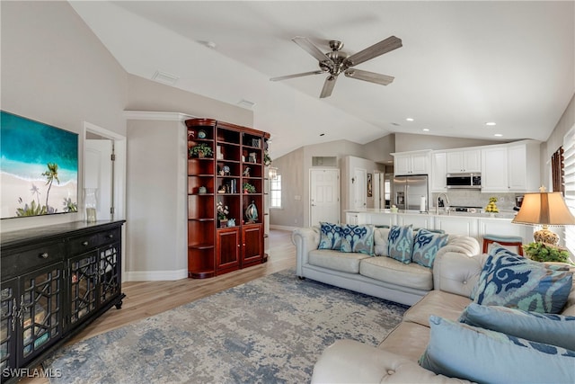 living room with lofted ceiling, ceiling fan, baseboards, and light wood-style floors