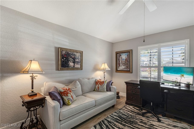 living area featuring wood finished floors, a ceiling fan, and baseboards