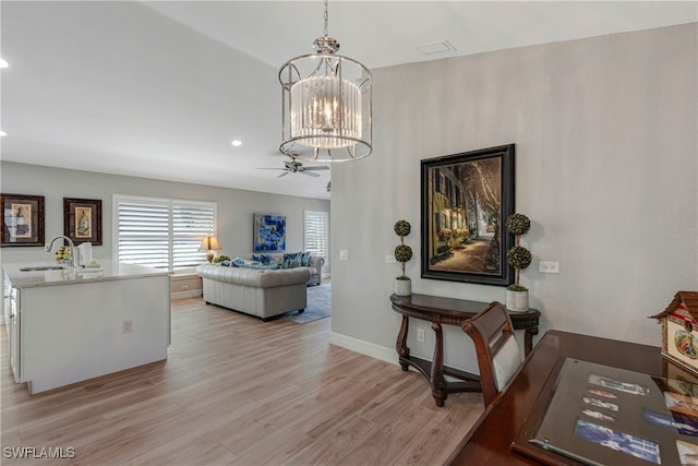 living room with ceiling fan with notable chandelier, recessed lighting, light wood-style flooring, and baseboards