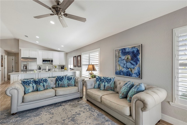 living area with light wood finished floors, baseboards, lofted ceiling, ceiling fan, and recessed lighting