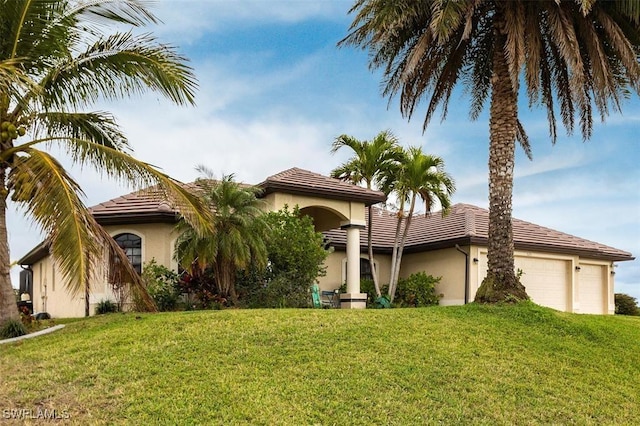 view of front of house featuring a garage, stucco siding, a tile roof, and a front yard