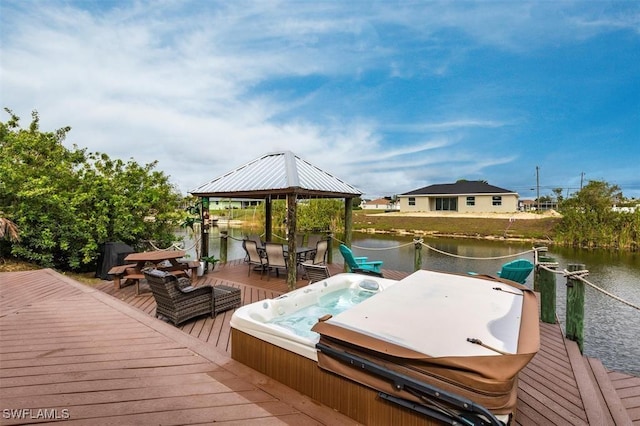 deck with outdoor dining space, a water view, hot tub deck surround, and a gazebo