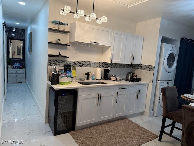 kitchen with stacked washing maching and dryer, beverage cooler, marble finish floor, and tasteful backsplash