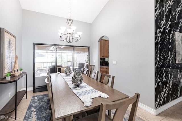 dining area with arched walkways, a notable chandelier, light tile patterned floors, high vaulted ceiling, and baseboards