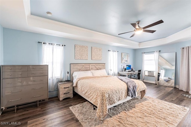 bedroom featuring a tray ceiling, multiple windows, and wood finished floors