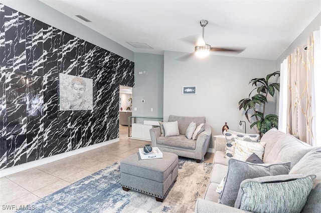 tiled living room with ceiling fan, an accent wall, visible vents, baseboards, and wallpapered walls