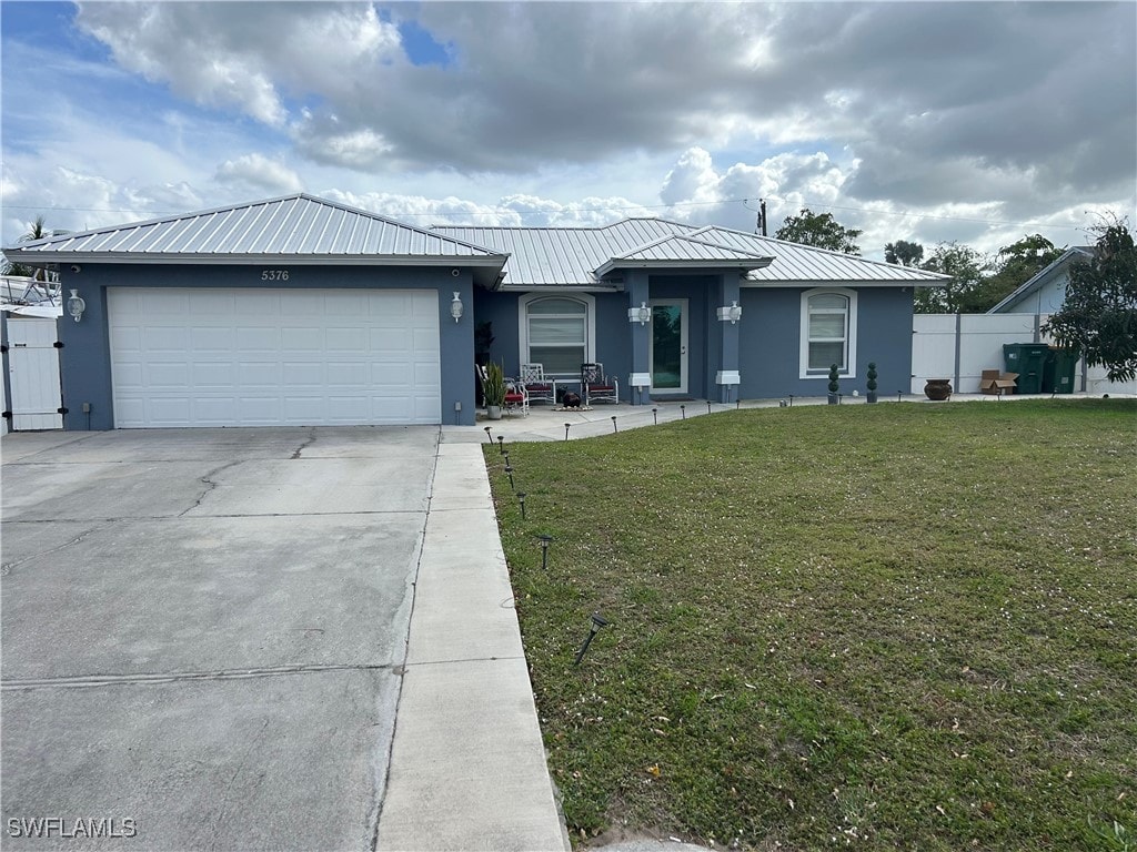 view of front of property with driveway, a garage, a front yard, and stucco siding