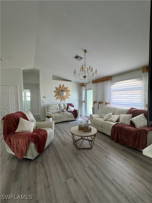 living area featuring visible vents, an inviting chandelier, and wood finished floors