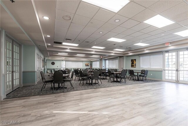 unfurnished dining area featuring a drop ceiling, wood finished floors, visible vents, baseboards, and french doors