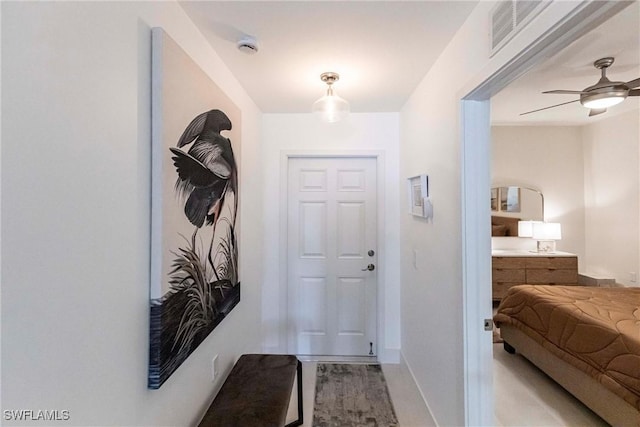 doorway featuring a ceiling fan, visible vents, and baseboards