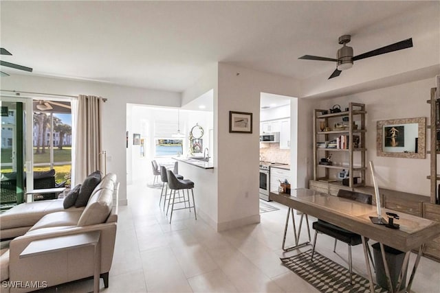 living area featuring ceiling fan and baseboards