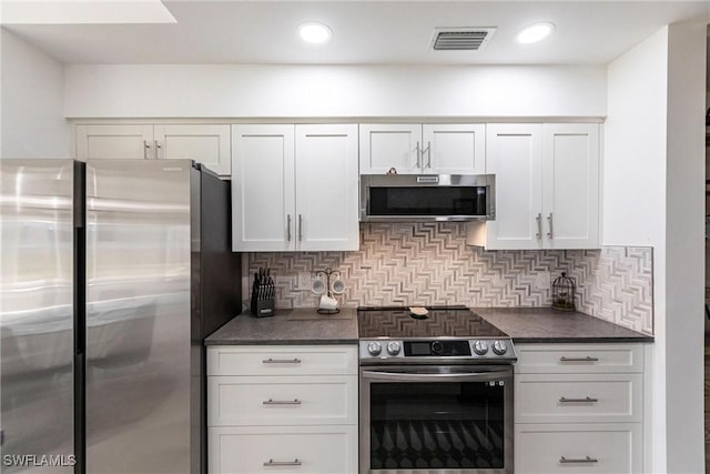 kitchen with dark countertops, visible vents, appliances with stainless steel finishes, and backsplash