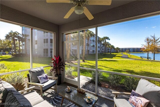 sunroom / solarium featuring a water view, a healthy amount of sunlight, and a ceiling fan