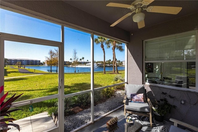 sunroom / solarium with a water view and ceiling fan