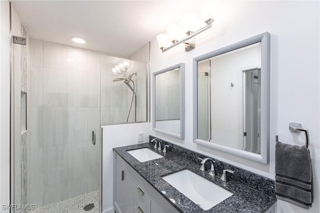 bathroom featuring double vanity, a stall shower, and a sink