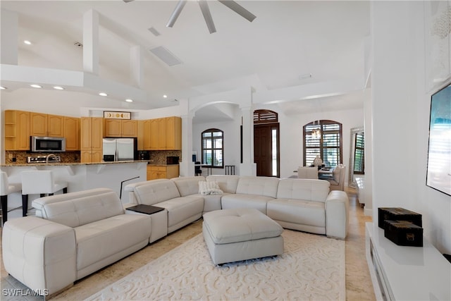 living area featuring a healthy amount of sunlight, high vaulted ceiling, decorative columns, and arched walkways