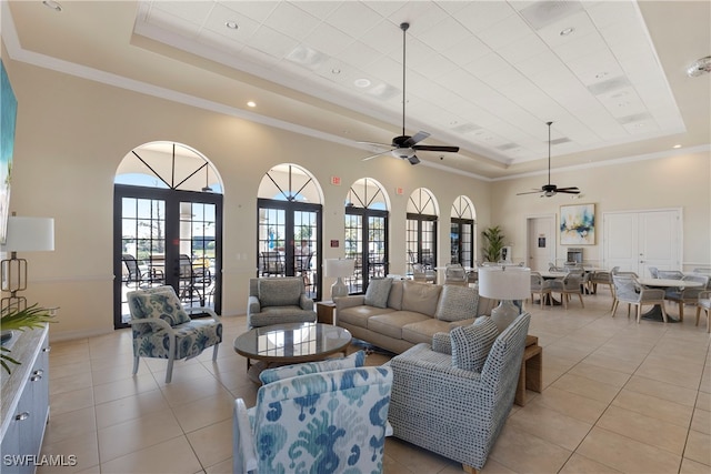 living area with a raised ceiling, a towering ceiling, french doors, and light tile patterned floors