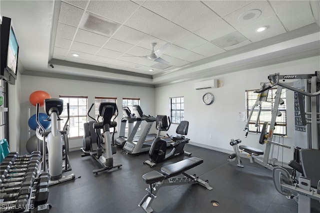 gym featuring a paneled ceiling, baseboards, a tray ceiling, and a wall mounted air conditioner