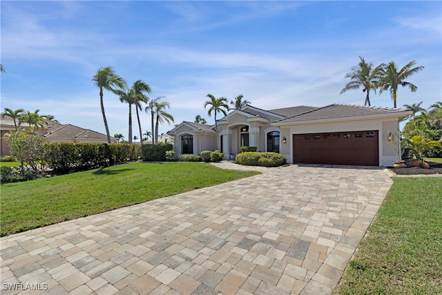 view of front of house with a garage, decorative driveway, a front lawn, and stucco siding