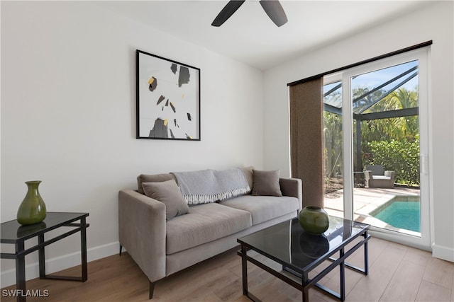 living room featuring ceiling fan, light wood-style flooring, and baseboards