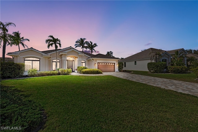 view of front facade featuring a garage, stucco siding, decorative driveway, and a yard