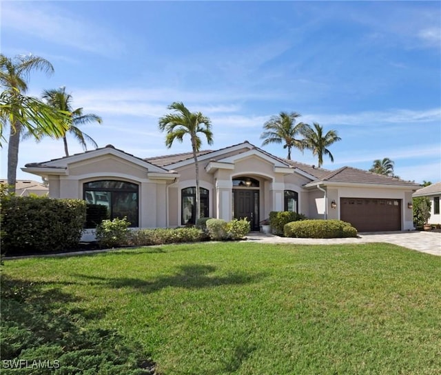 view of front of property featuring a garage, driveway, a front lawn, and stucco siding