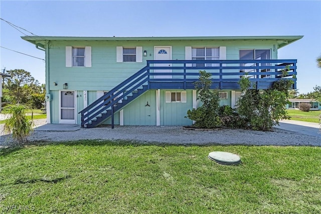 rear view of property with a lawn and stairs