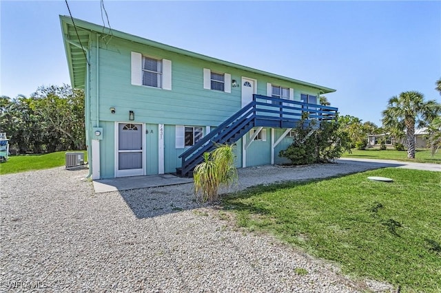 7431 Barrancas Ave, Bokeelia, FL 33922 - view of front facade with stairway, central AC unit, and a front lawn