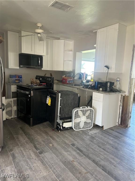 kitchen with visible vents, a sink, black appliances, and wood finished floors