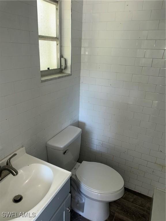 half bathroom featuring toilet, tile walls, and vanity