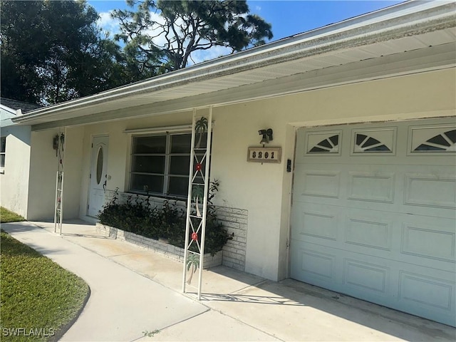 doorway to property featuring covered porch, concrete driveway, and stucco siding