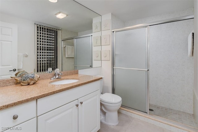 bathroom featuring toilet, a stall shower, vanity, and tile patterned floors