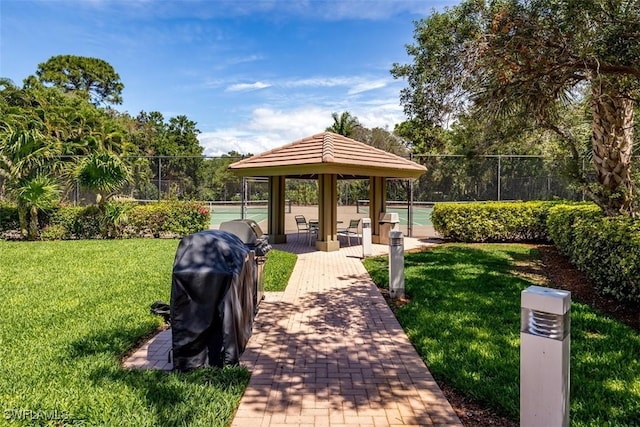 surrounding community with a yard, fence, and a tennis court