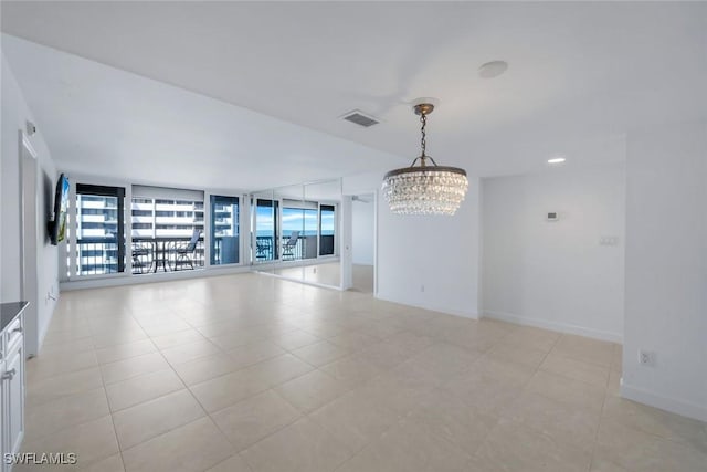 empty room with floor to ceiling windows, light tile patterned floors, visible vents, a chandelier, and baseboards