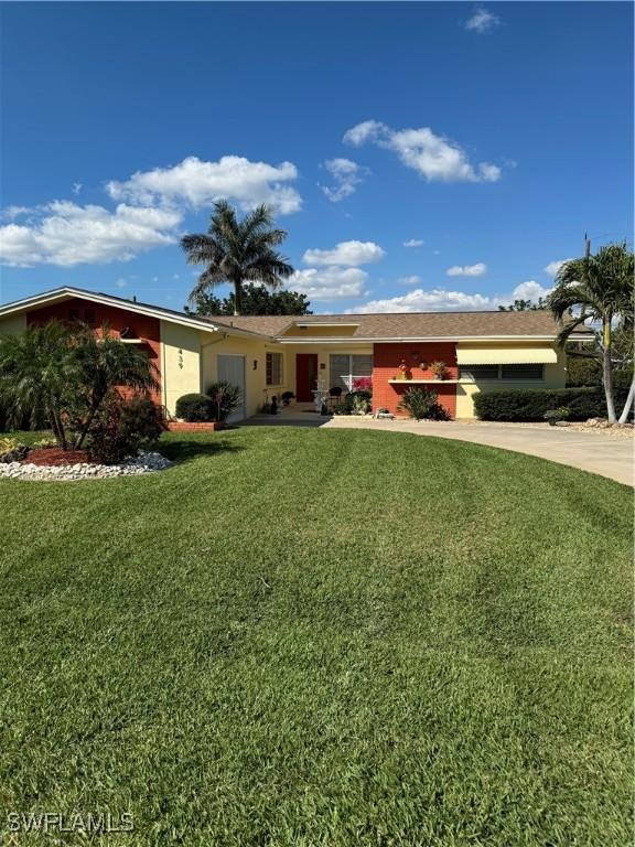 ranch-style house with driveway, a front lawn, and stucco siding