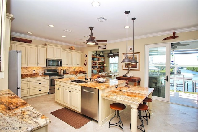 kitchen with appliances with stainless steel finishes, cream cabinets, a sink, and visible vents